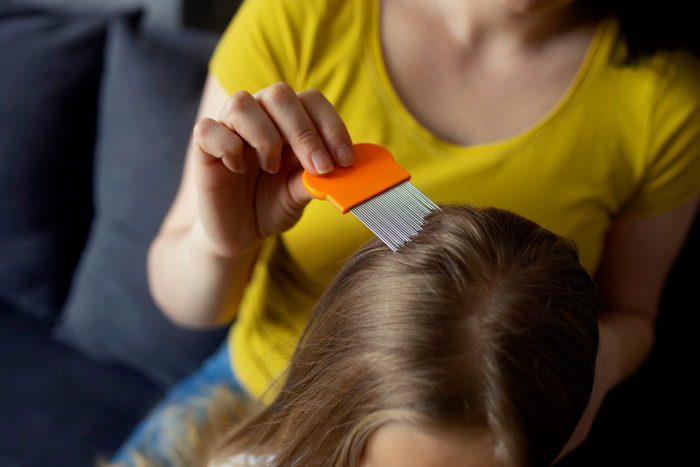 Mère utilisant un peigne anti-poux pour retirer les poux des cheveux d'une enfant