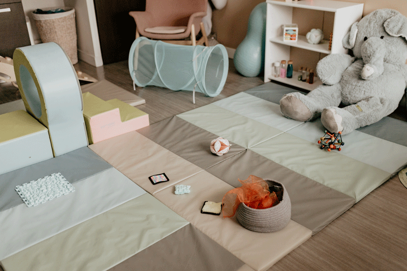 Espace de motricité aménagé avec des tapis colorés et des jouets adaptés pour les ateliers bébé.