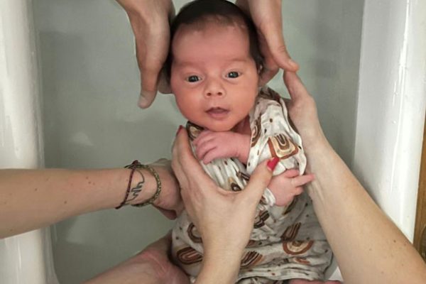 Bébé dans un bain coco chiro, entouré de mains sécurisantes pour libérer les tensions et favoriser le bien-être.
