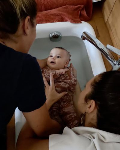 Un bébé dans un bain thalasso, entouré de deux personnes assurant un moment de détente et de sécurité.