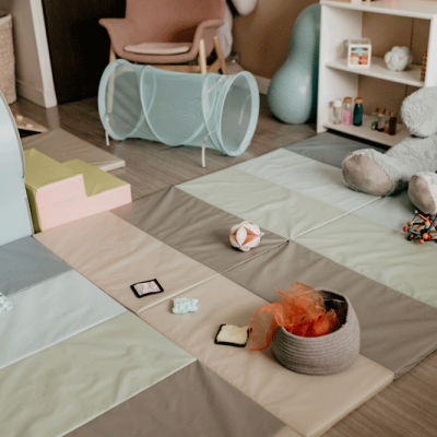 Espace de motricité aménagé avec des tapis colorés et des jouets adaptés pour les ateliers bébé.