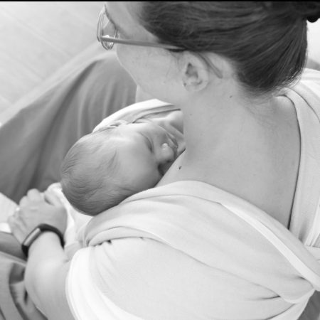 Mère portant son bébé dans une écharpe de portage, moment de calme et de proximité