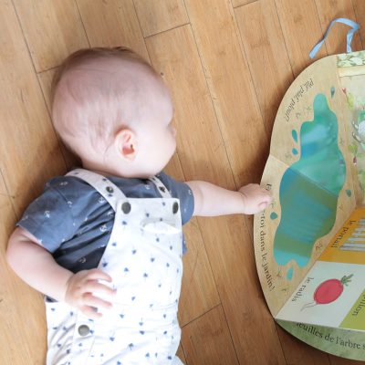 Bébé explorant librement un livre sur le sol, démontrant l'importance de l'environnement adapté pour la motricité libre.